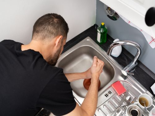 a plumber from 5 Star Plumbing Services is cleaning the drain